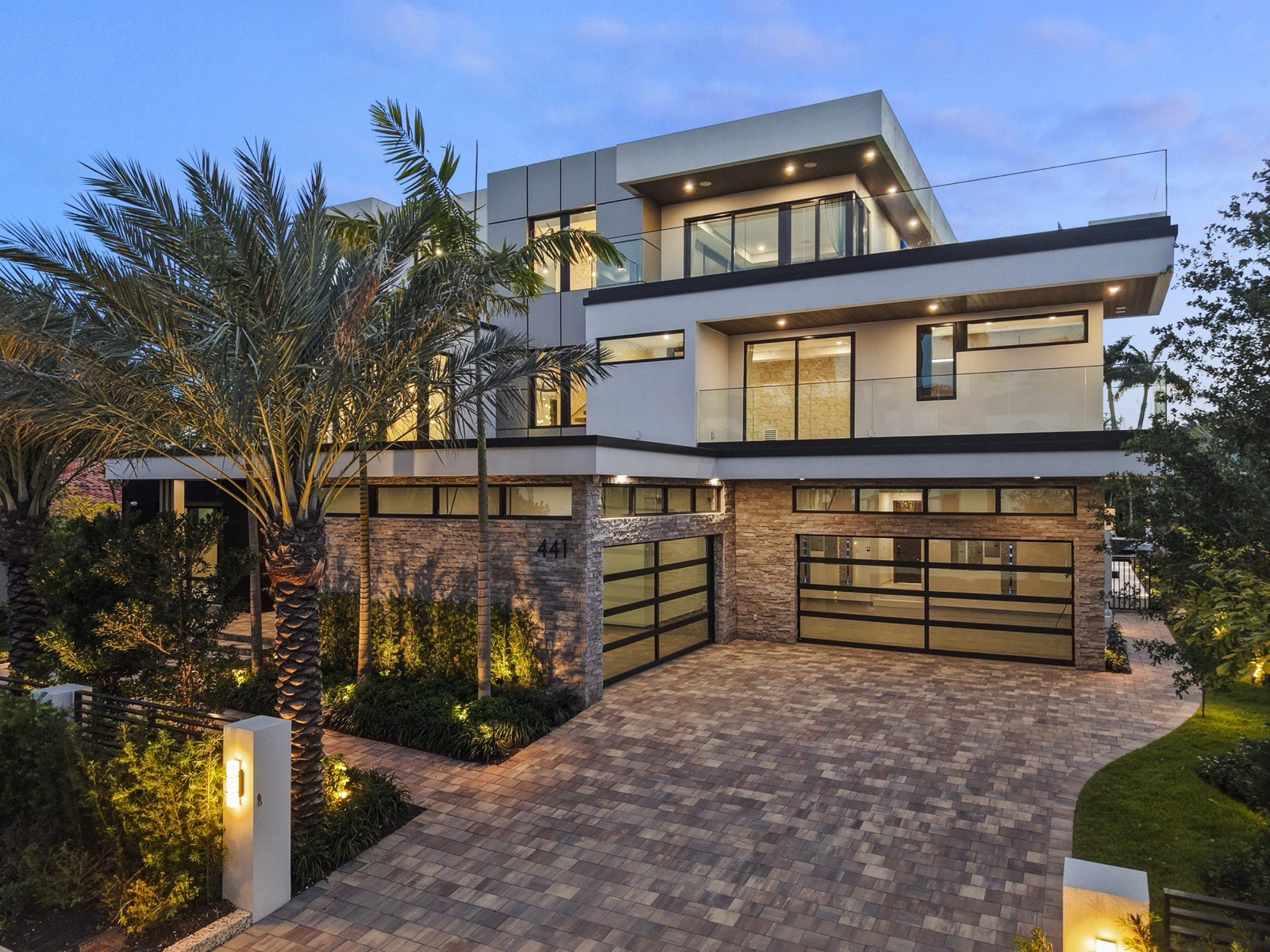 Front elevation with palms, paver motor court, and glass garage doors